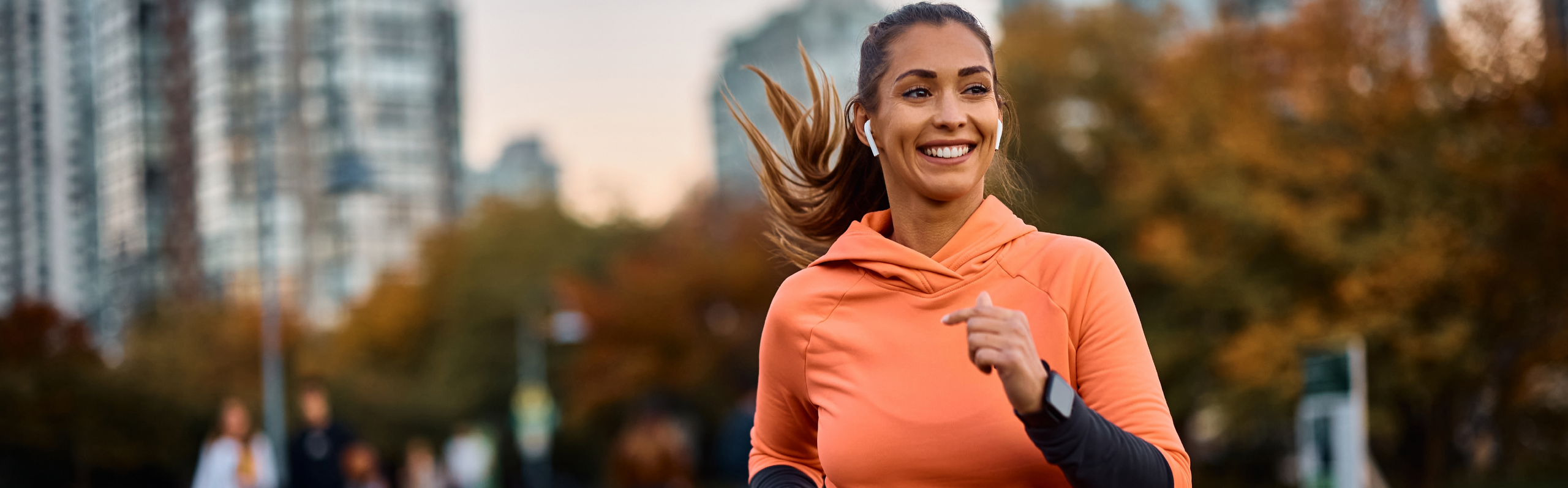 Frau joggt durch einen Park und lächelt.